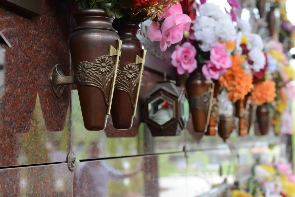 Close up view of crypt faces inside cemetery mausoleum, showing flowers.